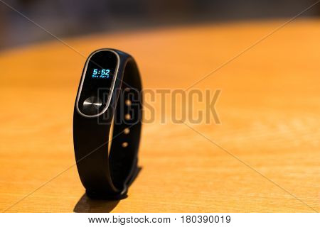 A clock of fitness smart band device on wooden table