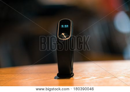 A clock of fitness smart band device on wooden table