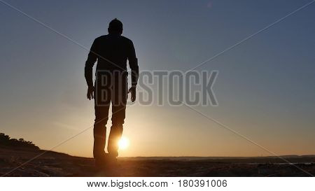 freedom. Man stands on a cliff sunset silhouette hand in sides lifestyle