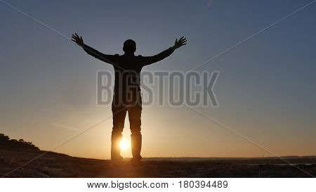 freedom. Man stands on cliff sunset silhouette hand lifestyle in the sides
