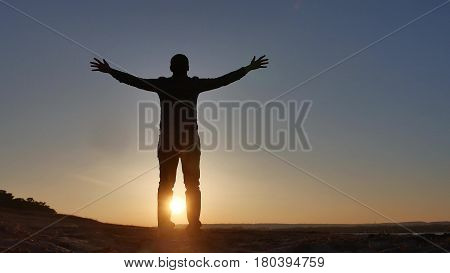 freedom. Man stands on cliff sunset silhouette hand lifestyle in the sides