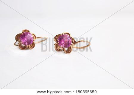Gold earrings with a pink jewel on a white background.