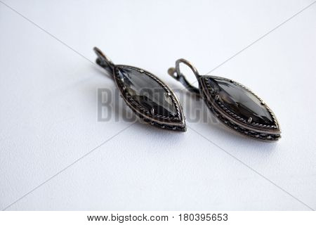 Silver earrings with a black gem on a white background