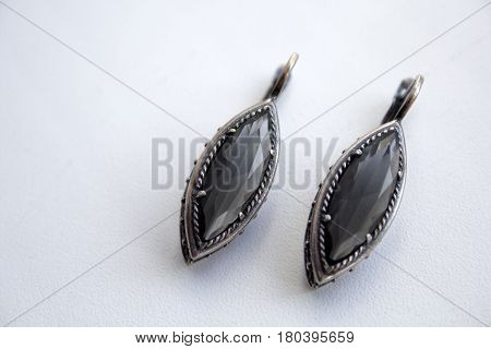 Silver earrings with a black gem on a white background