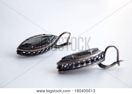 Silver earrings with a black gem on a white background