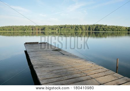 Wooden pier on a lake in the afternoon in windless weather