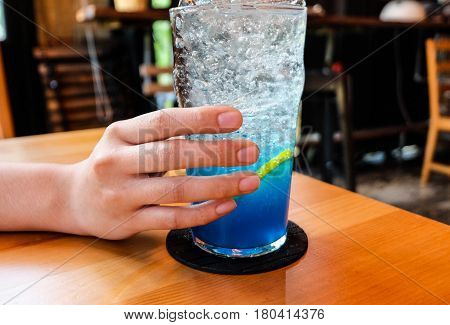 Young Woman Handle  Glass Of Splash Blue Lemon Juice Soda On The Wood Table, Suumer And Fresh Concep