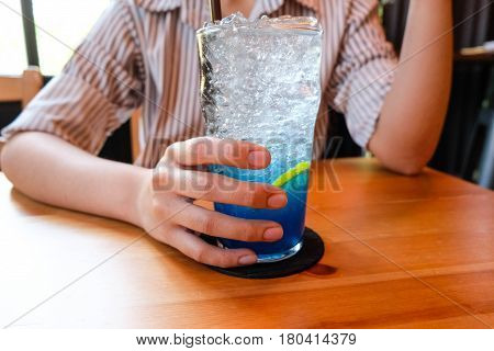 Young Woman Handle  Glass Of Splash Blue Lemon Juice Soda On The Wood Table, Suumer And Fresh Concep