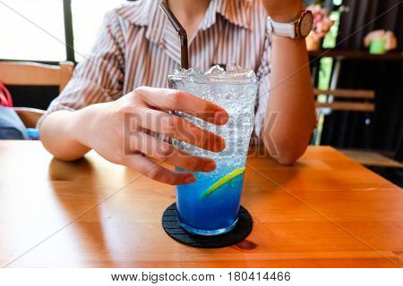 Young Woman Handle  Glass Of Splash Blue Lemon Juice Soda On The Wood Table, Suumer And Fresh Concep