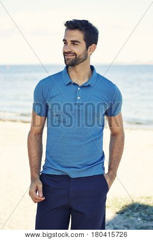 Guy in blue polo shirt on beach smiling