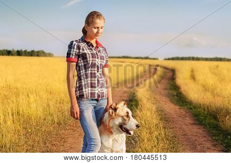 Women and central Asian shepherd walk in the park. He keeps the dog on the leash.