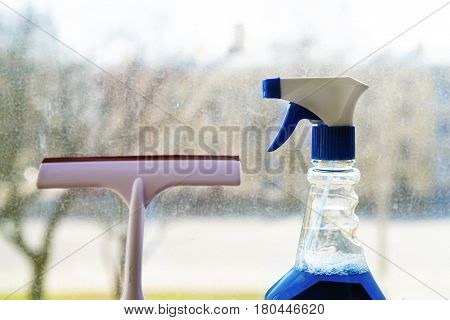 Tools for window cleaning. Cleaning spray and squeegee on a dirty window background.