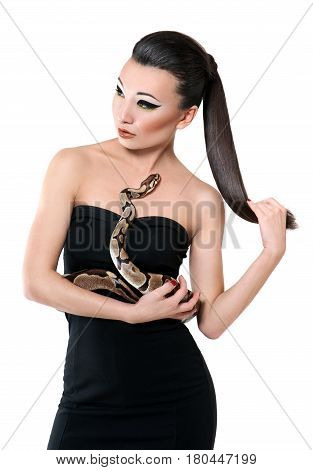 Vertical portrait of a beautiful sexy brunette wearing professional makeup and little black dress posing elegantly with a snake in her hands looking away isolated beauty fashion ethnic sexy seductive.