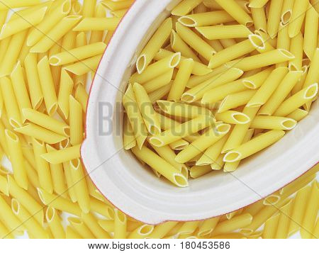 Organic raw penne pasta in the blow on white background