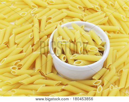 Organic raw penne pasta in the blow on white background