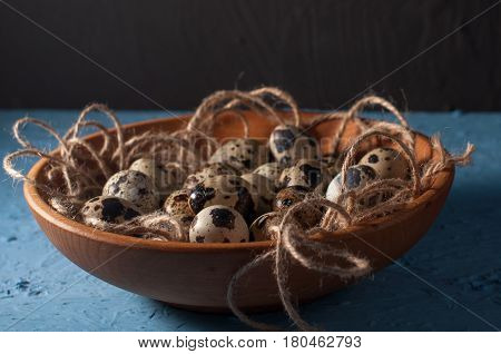 Quail Eggs In Wooden Bowl Isolated On Blue Background Close Up