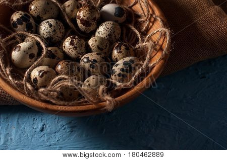 Quail Eggs In Wooden Bowl Isolated On Blue Background Close Up