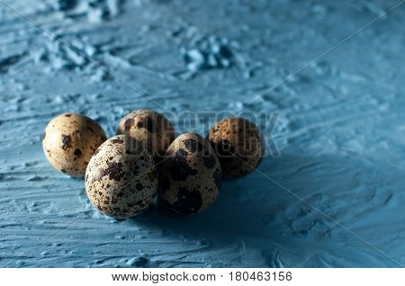 pile of quail eggs against blue background close up