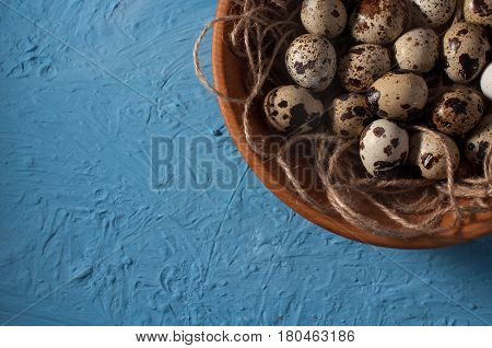 Quail Eggs In Wooden Bowl Isolated On Blue Background Close Up