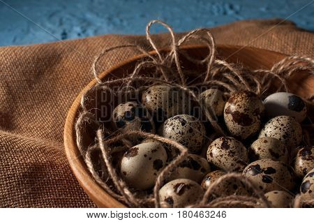 Quail Eggs In Wooden Bowl Isolated On Blue Background Close Up