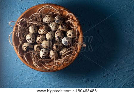 Quail Eggs In Wooden Bowl Isolated On Blue Background Close Up
