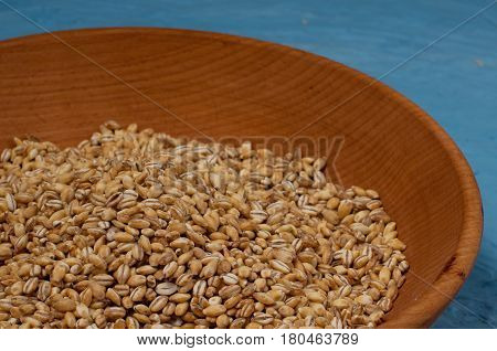 Wooden Bowl With Pearl Barley Isolated On Blue Background. Close-up.