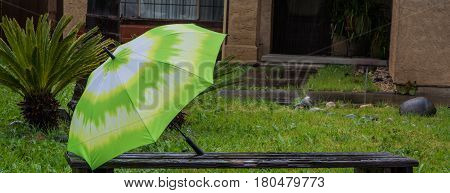 Green an White Umbrella sitting on a Bench