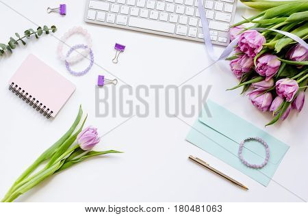 Spring pink flowers on workdesk at home ofiice white background top view mockup