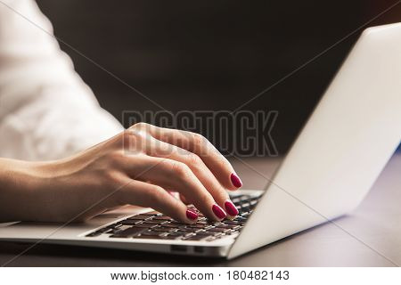 Side view of businesswoman's hands using laptop at wokrplace. Electronic device concept