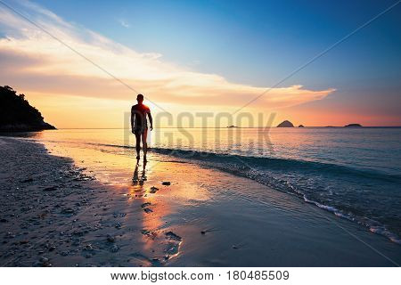 Lonely man walking on the tropical beach during amazing sunset. Perhentian islands Malaysia