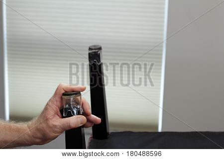 One hand installing one clear plastic and felt chair floor protector. Male hand placing a chair bottom floor protector on ta bottom of a dining room chair