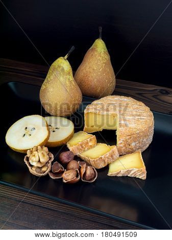 Soft washed-rind cheese walnut hazelnuts and pears on the black plate