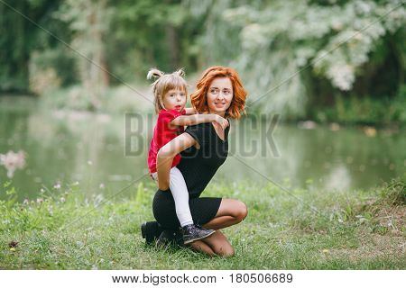 mom and little daughter walking in green summer park