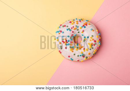 one tasty donut with white glaze isolated on pink-yellow background