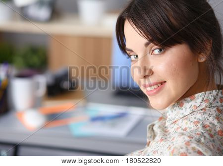 Portrait of young woman sitting at desk .