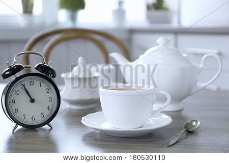 Retro alarm clock showing five minutes to eleven on lunch table