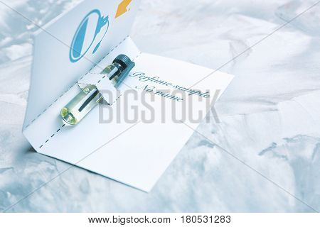 Perfume sample in paper cover on light background
