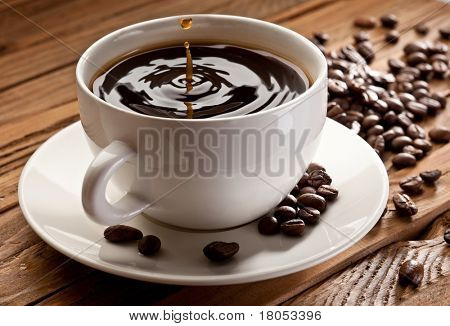 Goccia che cade in una tazza di caffè. Su fondo in legno