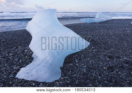 Ice breaking from glacier on black rock sand beach skyling Iceland winter landscape background