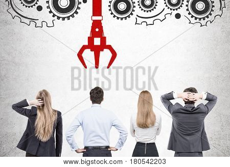 Rear view of businesspeople standing near a concrete wall with a conveyor belt and a grappling hook. Concept of HR.