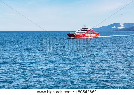 Keramoti, Greece - May 1, 2016: Red ferry boat going to Thassos from Keramoti port, blue sea and sky