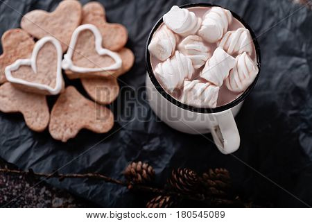 A cup of hot cocoa marshmallows and cookies and heart marshmallows cinnamon sticks