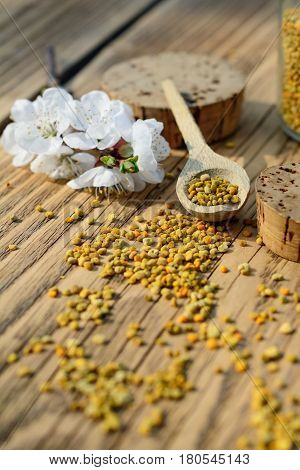 Bee pollen in a wooden spoon and flowers of spring trees. Apitherapy. Bee products