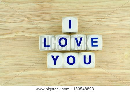 Blue Alphabets on White Cube Blocks say I LOVE YOU on the Wooden Surface Background