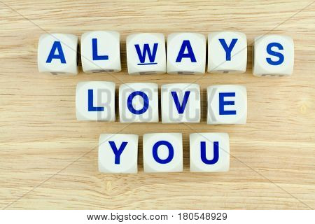 Blue Alphabets on White Cube Blocks say ALWAYS LOVE YOU on the Wooden Surface Background