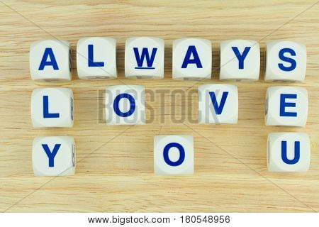 Blue Alphabets on White Cube Blocks say ALWAYS LOVE YOU on the Wooden Surface Background