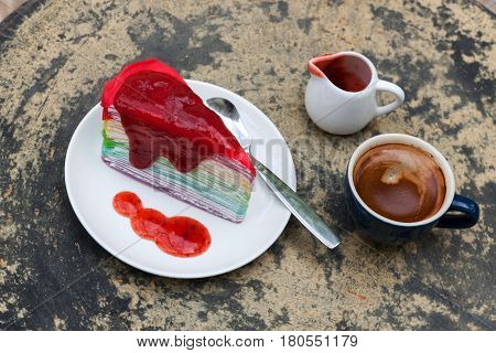 crepe cake rainbow and hot espresso coffee in garden side home. crape cake with strawberry sauce