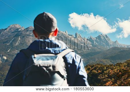 Man with backapack in mountains. Young traveler climbing to Mount Kinabalu in Malaysia.