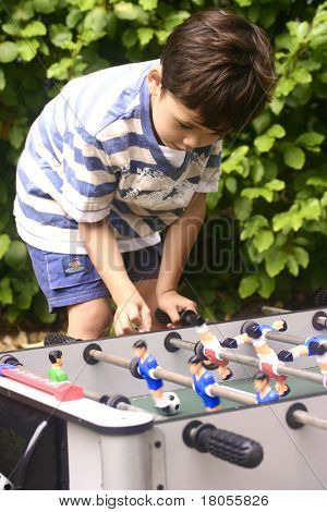 Een jonge jongen concurreren met zijn vriend op mini tafelvoetbal in de tuin