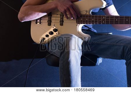 the man plays bass guitar on a black background, the music concept, beautiful lighting on the stage, closeup